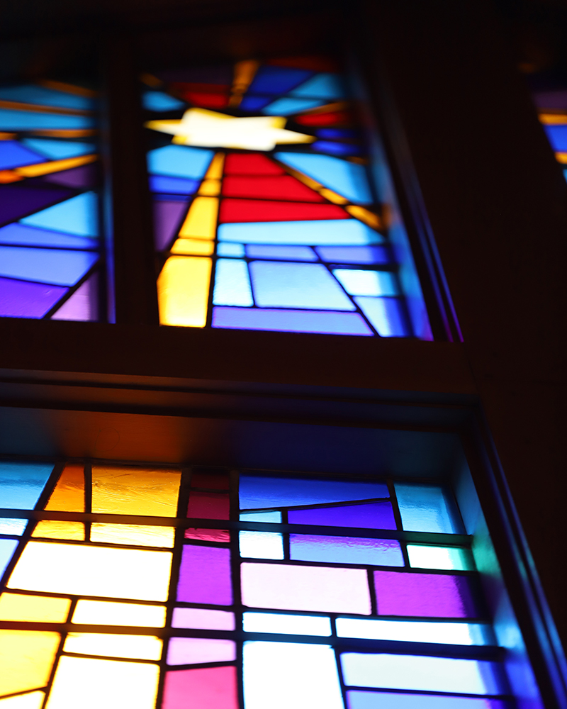 A close-up of a stained glass window made up of triangle shapes